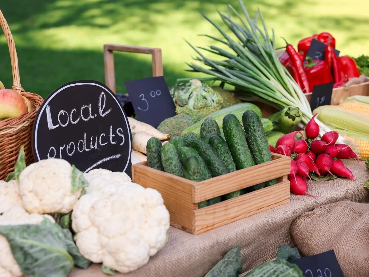 Fresh vegetables on a market table under a Local Products sign