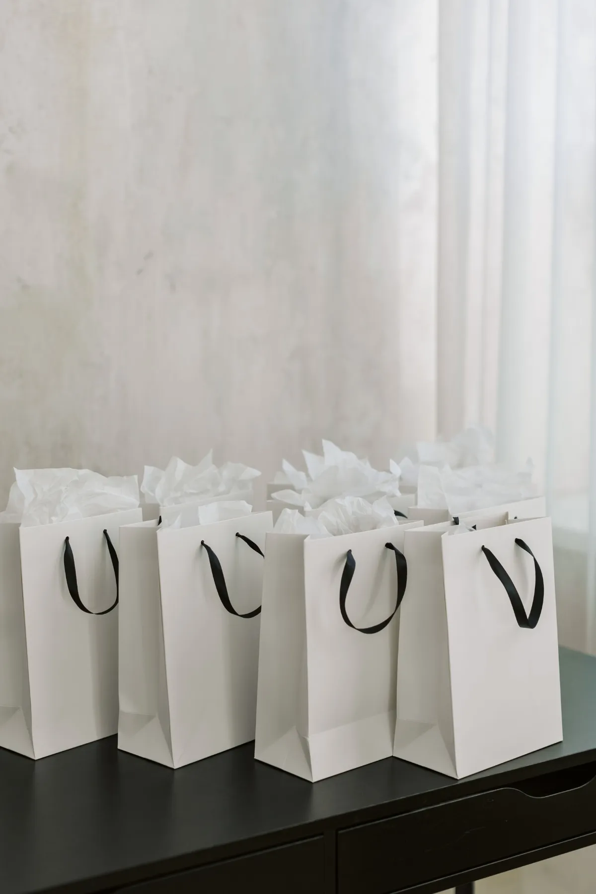 White gift bags lined up on a table